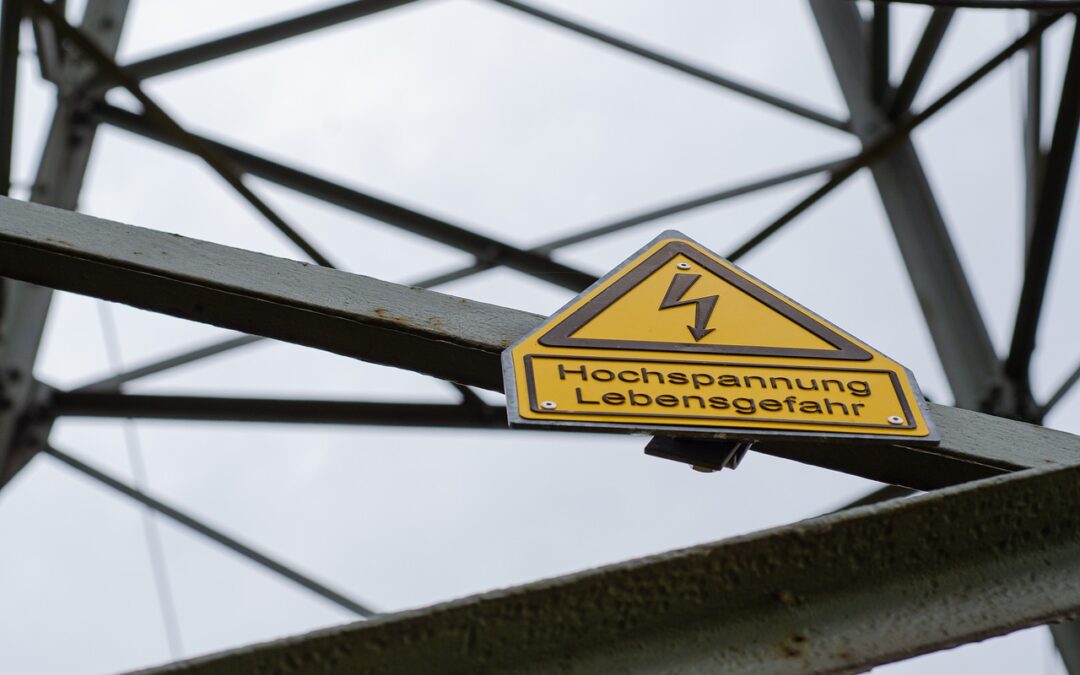 Strommasten mit dem Schild "Hochspannungsleitung! Lebensgefahr!"