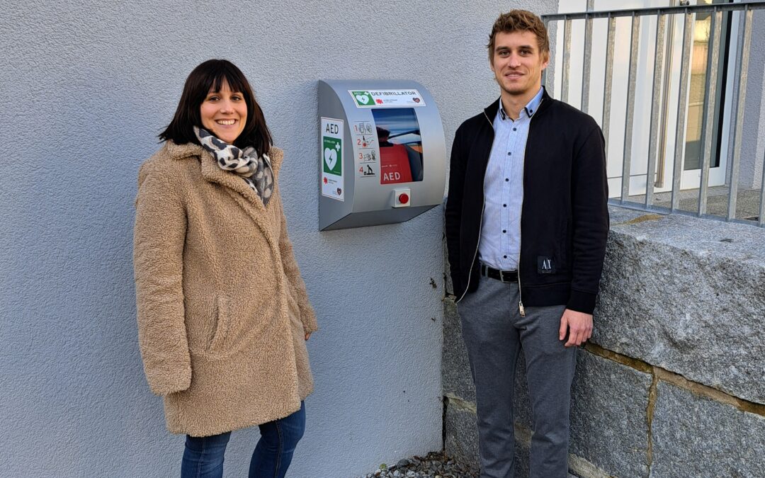 Rechts im Bild ist Bürgermeister Felix Hezel; links Anna-Kathrin Digeser (Mitarbeiterin Hauptamt). Sie nehmen den Defibrillator in Betrieb.