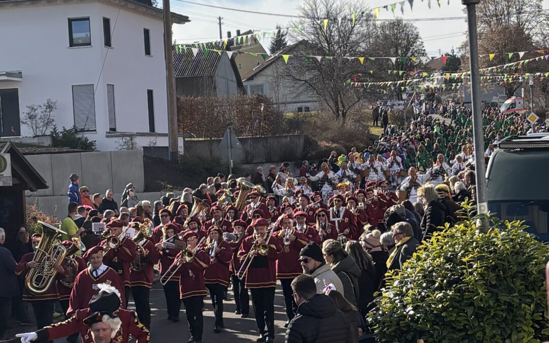 Foto vom G4-Treffen am 08.02. in Irslingen. Zu sehen ist der Musikverein Irslingen und die Schellnarren. Es stehen viele Zuschauer am Straßenrand bei Sonnenschein